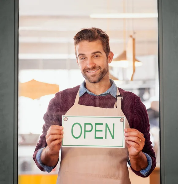 Entrez donc. Portrait d'un jeune propriétaire d'entreprise debout à la porte de son café avec un panneau ouvert. — Photo