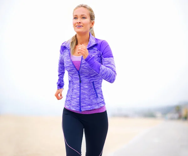 Wordt fitter met de stap. Opname van een jonge vrouw in sportkleding op het strand. — Stockfoto