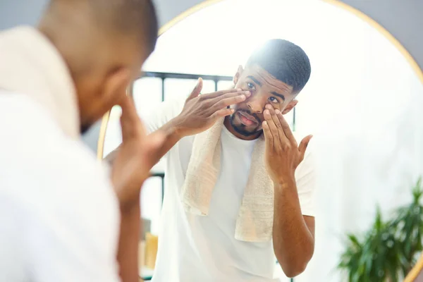 Esta crema facial fue muy recomendable. Hombre joven aplicando producto facial en su espejo de baño. — Foto de Stock
