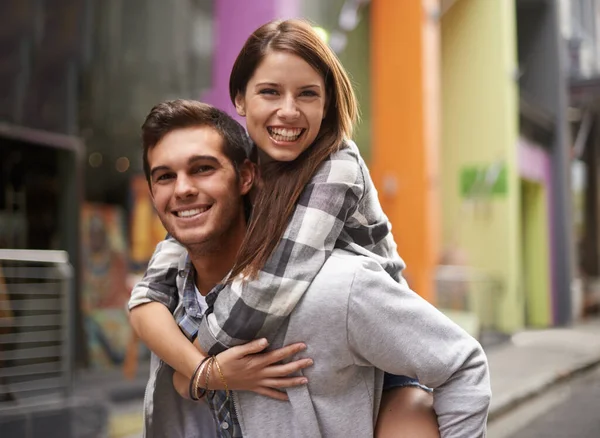 Totalement amoureux. Un jeune homme souriant tout en tirant sur sa copine dans la rue. — Photo