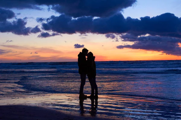 大自然为浪漫设定了场景。夕阳西下，一对恋人在海滩上接吻. — 图库照片