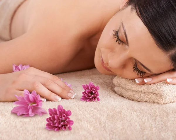 A beleza natural começa com a pausa. Vista cortada de uma jovem mulher relaxando em um spa com uma flor fresca nas proximidades. — Fotografia de Stock