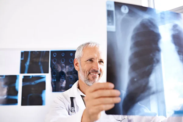 Все, здається, тут впорядковано. Знімок зрілого лікаря-чоловіка, який посміхається, дивлячись на рентгенівське зображення в лікарні . — стокове фото