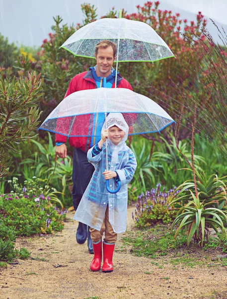 Caminando bajo la lluvia. Largura completa de un padre y su hijo caminando afuera bajo la lluvia. — Foto de Stock