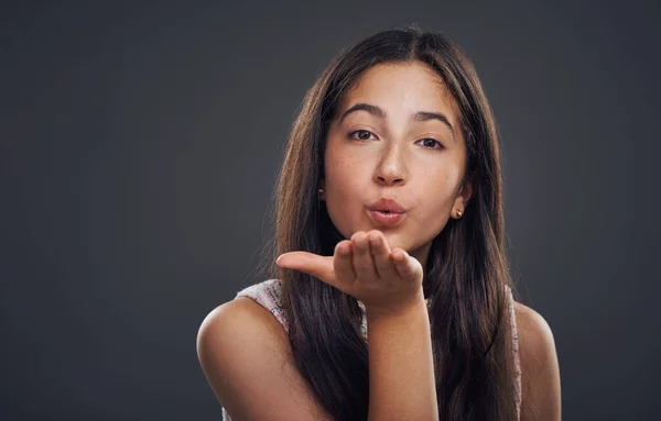 Répandez l'amour. Portrait recadré d'une jolie adolescente debout seule et baisers soufflant sur un fond sombre studio. — Photo