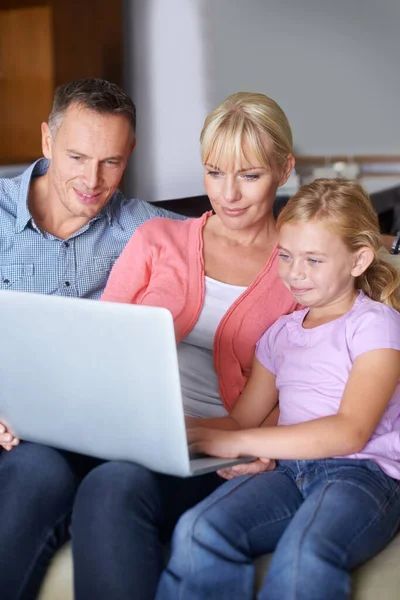 Vinculación familiar. Una familia de tres usando un portátil en el salón. — Foto de Stock