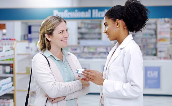 Рішення для здоров'я, які змушують вас усміхатися весь день. Знімок молодого фармацевта, який рекомендує продукт охорони здоров'я молодій жінці в аптеці . — стокове фото