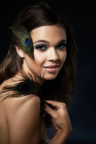 Feminine beauty. A gorgeous young woman with dramatic eye makeup holding a peacock feather. — Stock Photo, Image