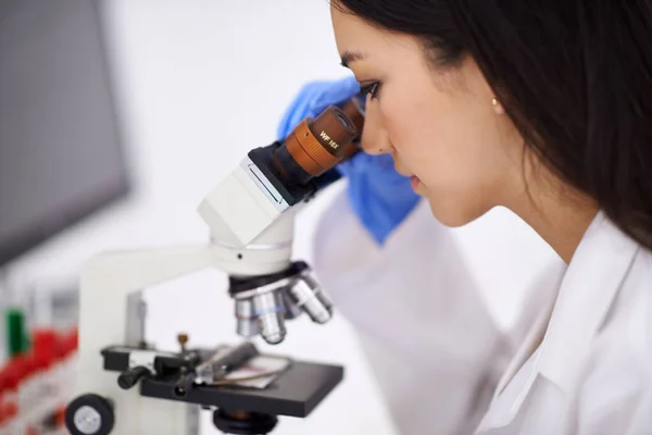 Ela é uma profissional no trabalho de sangue. Perfil de uma cientista que visualiza uma amostra através de um microscópio. — Fotografia de Stock