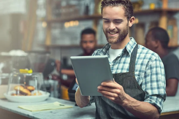 Media społecznościowe sprzyjają poprawie widoczności małych przedsiębiorstw. Zdjęcie młodego człowieka używającego tabletu cyfrowego w sklepie, w którym pracuje.. — Zdjęcie stockowe