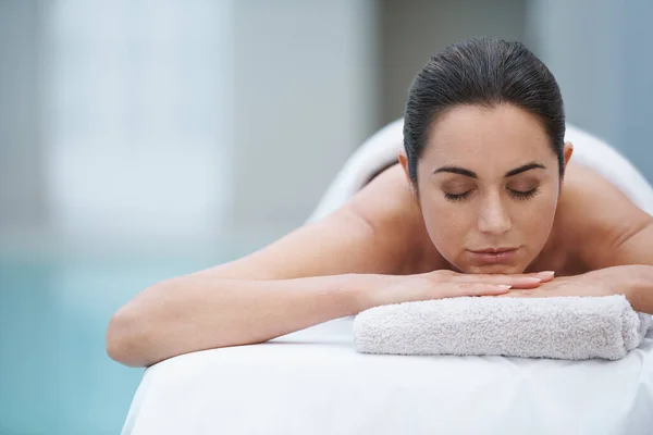 Miłego dnia w spa. Ujęcie pięknej kobiety leżącej na stole do masażu przy basenie. — Zdjęcie stockowe