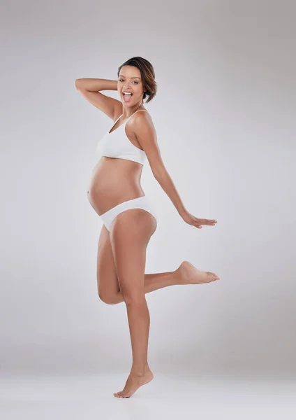 Mes corps ont changé et j'adore ça. Portrait studio d'une belle jeune femme enceinte posant sur un fond gris. — Photo