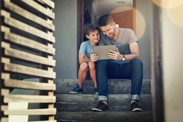 Teaching his little guy about an online world. Shot of a father and son using a digital tablet together on the front steps of their home. — Stock Photo, Image