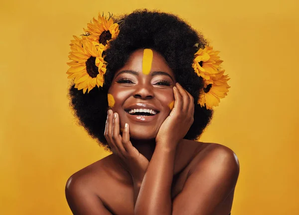 We hebben allemaal zonnebloemen nodig in ons leven. Studio portret van een mooie jonge vrouw glimlachend terwijl poseren met zonnebloemen in haar haar tegen een mosterd achtergrond. — Stockfoto