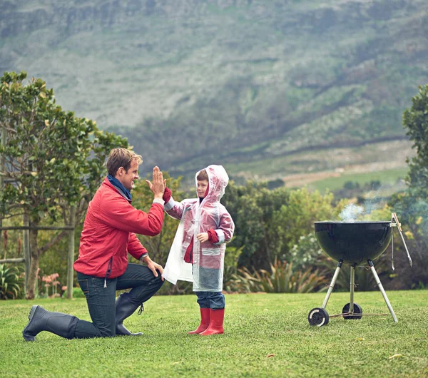 Dá cá mais cinco. Tiro de um pai dando a seu filho um alto cinco enquanto eles estão tendo um churrasco lá fora. — Fotografia de Stock