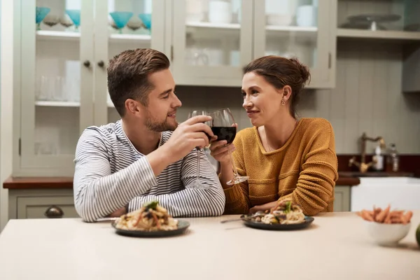 Por nuestras grandes habilidades culinarias. Foto de una pareja joven y cariñosa haciendo un brindis mientras comen en su cocina en casa. — Foto de Stock
