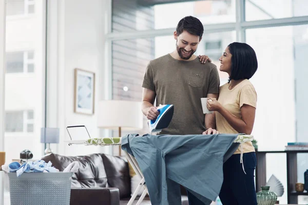 Die Aufteilung der Hausarbeit ist der einfachste Weg zu häuslicher Glückseligkeit. Aufnahme eines glücklichen jungen Paares, das zu Hause gemeinsam frisch gewaschene Wäsche bügelt. — Stockfoto