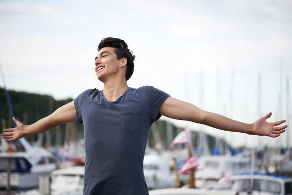 自由で生きている感じ。風を楽しむために腕を伸ばして若い男. — ストック写真