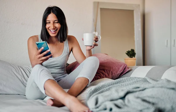 Sabahları kahve ve sosyal medya içindir. Genç bir kadının akıllı telefon kullanması ve evde bir fincan kahvenin tadını çıkarması.. — Stok fotoğraf