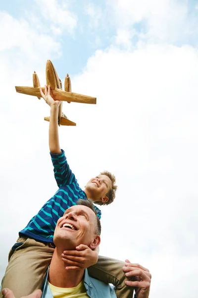 Dając ucieczkę jego synom wyobraźni. Strzał chłopca bawiącego się zabawkowym samolotem, podczas gdy jego ojciec wyciągał go na barana.. — Zdjęcie stockowe