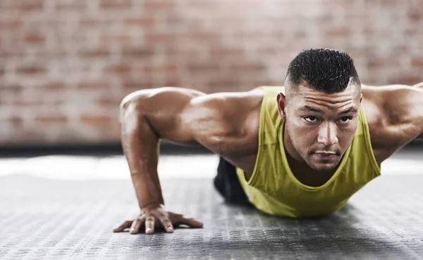 Tryck ner den till gränsen. Beskuren bild av en ung man som tränar i gymmet. — Stockfoto