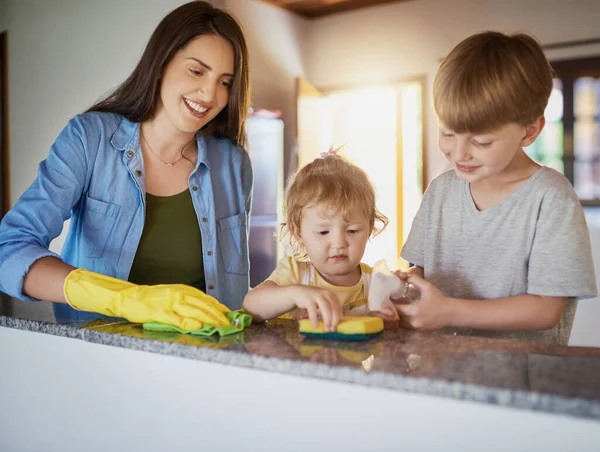 Fare le faccende domestiche è un ottimo modo per insegnare ai bambini la responsabilità. Girato di una madre e dei suoi due bambini piccoli che fanno le faccende insieme a casa. — Foto Stock