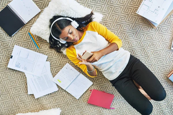 Mi prendo una pausa musicale. Colpo ad angolo alto di una giovane studentessa che studia a casa. — Foto Stock