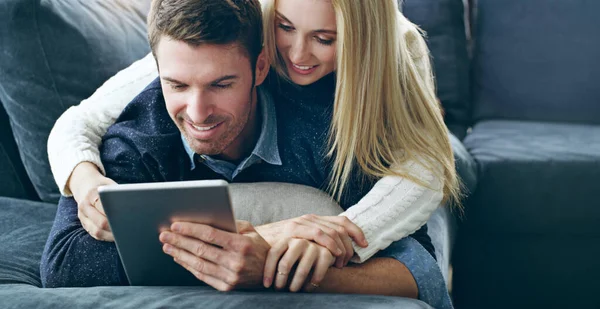 Laisse-moi voir. Plan recadré d'un jeune couple affectueux utilisant une tablette numérique alors qu'il était allongé sur son canapé à la maison. — Photo
