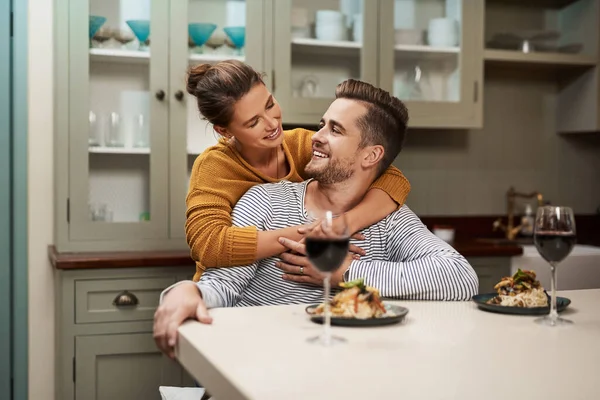 Seguro que conoce el camino al corazón de un hombre. Foto de una joven cariñosa abrazando a su marido durante la cena en su cocina en casa. — Foto de Stock
