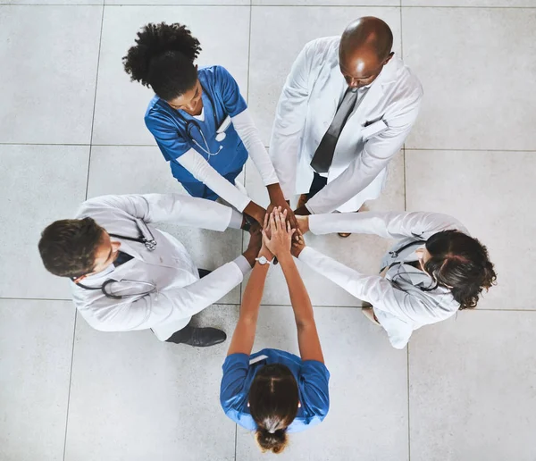 A bajtársiasság mindent megváltoztat az egészségügyben. Nagy látószögű felvétel egy sokszínű orvoscsoportról, akik egy kórházban fogják össze a kezüket.. — Stock Fotó