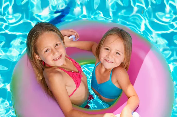 Rocas de verano. Dos niñas usando un tubo inflable mientras nadan. — Foto de Stock