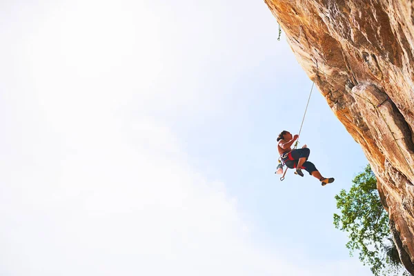 A vida é melhor vivida no limite. Tiro de um jovem alpinista escalando um penhasco. — Fotografia de Stock
