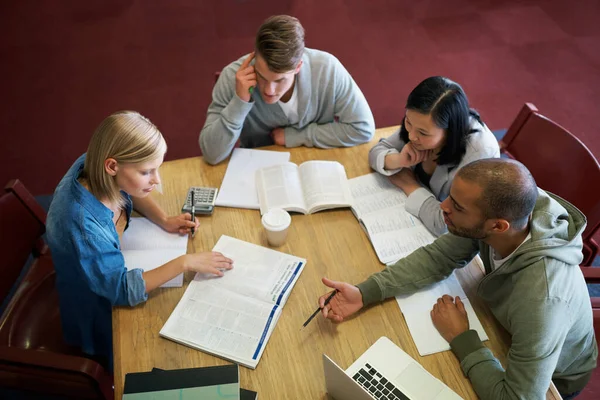 Cramming algum conhecimento de última hora. Um grupo de jovens que estudam juntos na biblioteca. — Fotografia de Stock