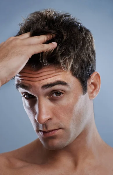 Bezorgd over zijn haar. Een jonge man die product aan zijn haar aanbrengt. — Stockfoto