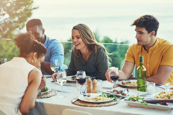 Siempre pasamos los mejores momentos juntos. Foto de un grupo de amigos disfrutando de una comida y bebidas juntos alrededor de una mesa en una reunión al aire libre. — Foto de Stock