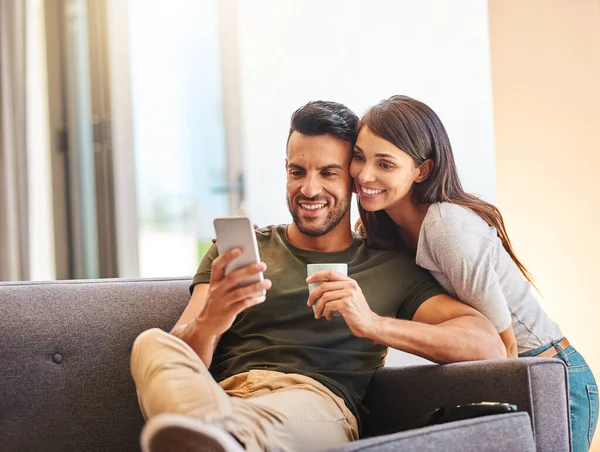 Entra para uma selfie, querida. Tiro de um jovem casal tomando selfies juntos em casa. — Fotografia de Stock