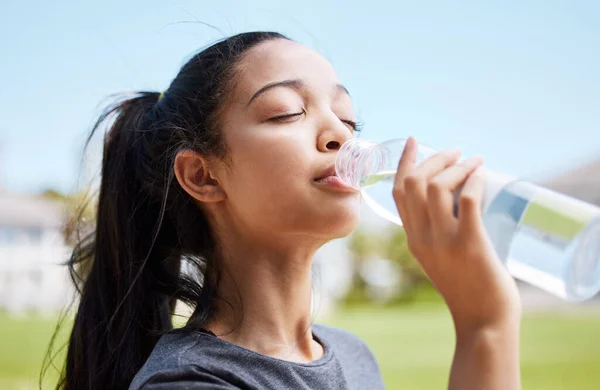 Water smaakt nooit lekkerder dan na het zweten. Schot van een jonge vrouw die water drinkt na haar training in het park.. — Stockfoto