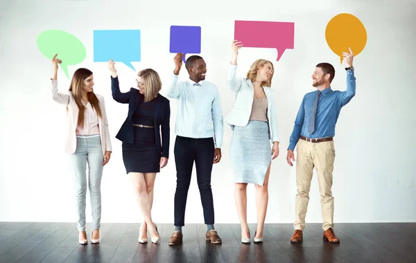 Sorry wat je zei. Opname van een groep collega 's die naast elkaar staan terwijl ze spraakbelletjes tegen een witte achtergrond houden. — Stockfoto