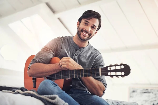 A prática é perfeita. Tiro de um jovem bonito que pratica guitarra em casa. — Fotografia de Stock