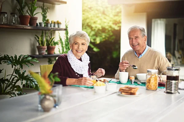 People who love breakfast are always the best people. Portrait of a happy senior couple enjoying breakfast together at home. — Stock Photo, Image