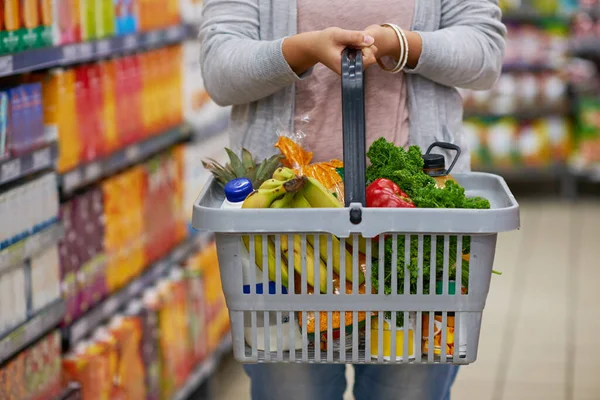 Rellenando un poco de frescura. Primer plano de una mujer sosteniendo una cesta llena de comestibles en un supermercado. —  Fotos de Stock