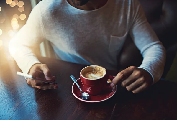 Αυτός ο καφές φαίνεται νόστιμος. Τραβηγμένη φωτογραφία ενός νεαρού να χρησιμοποιεί το κινητό του σε μια καφετέρια.. — Φωτογραφία Αρχείου