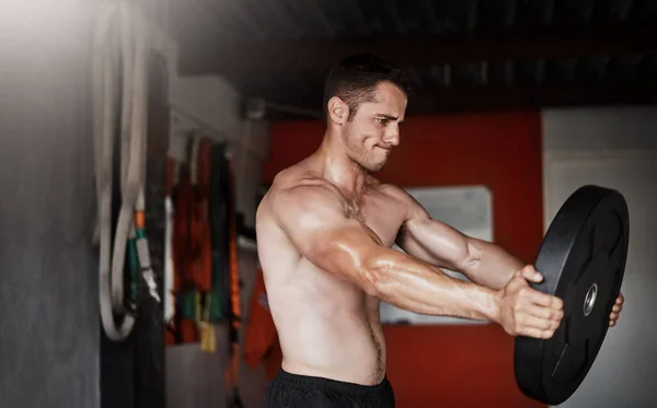 Usando el equipo a su disposición. Recortado tiro de un joven guapo y musculoso haciendo ejercicio con un peso en el gimnasio. — Foto de Stock