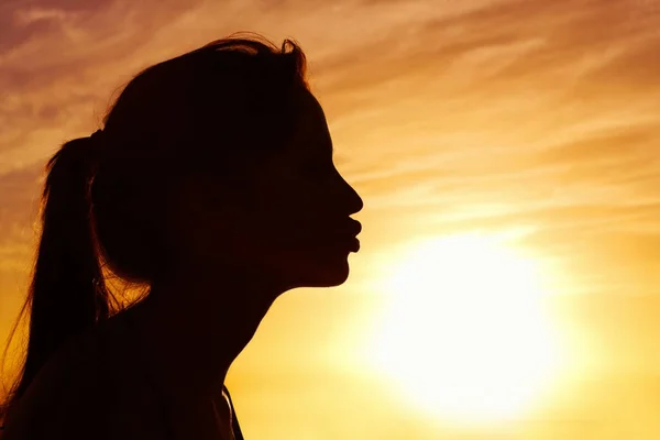 Primo piano di una donna che bacia il sole contro un bel cielo. Profilo di una donna che bacia il sole contro il bel cielo. — Foto Stock