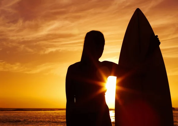 Силует жінки, яка тримає дошку для серфінгу на заході сонця. Силует красивої жінки, що тримає дошку для серфінгу на заході сонця . — стокове фото