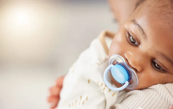 Shes my little miracle, my whole world. Shot of an adorable baby girl sucking a dummy while being held by her mother at home. — Stock Photo, Image