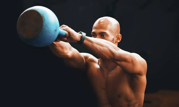 Die Kettlebell-Schaukel trifft fast alles im Körper. Aufnahme eines muskulösen jungen Mannes, der in einem Fitnessstudio mit einer Kettlebell trainiert. — Stockfoto
