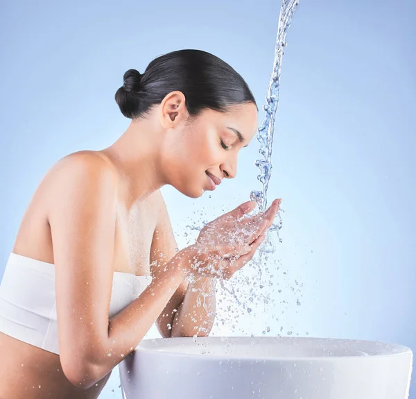 La cura della pelle è una parte importante della cura di sé. Girato di una giovane donna che si lava su uno sfondo blu. — Foto Stock
