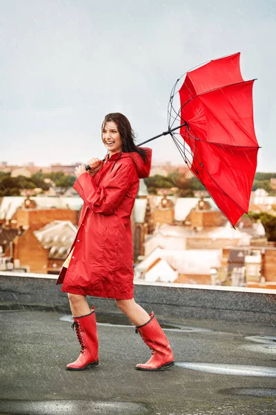 Dem Sturm mit einem Lächeln begegnen. Junge Frau lacht, während sie auf einem Dach von Regen und Wind getroffen wird. — Stockfoto