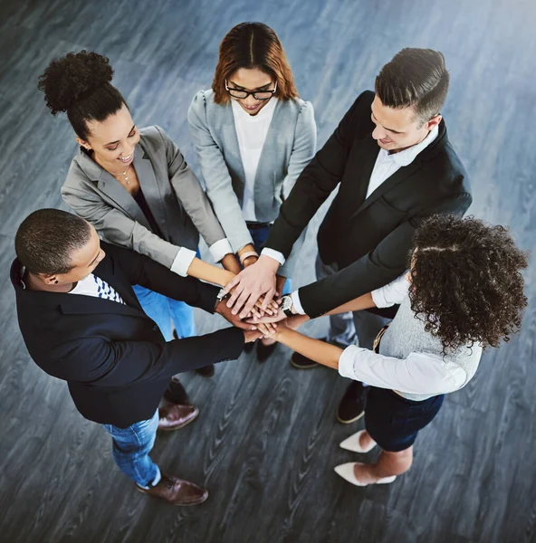 Teamwork overtroeft alles. Hoge hoek opname van een groep zakenmensen die hun handen samenvoegen in een bundel. — Stockfoto